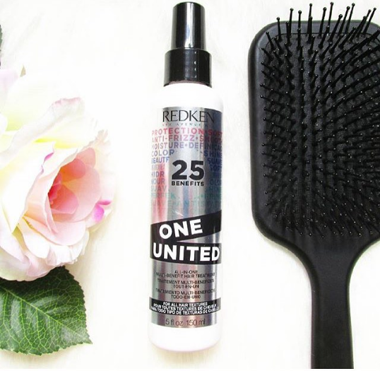 Redken One United Leave In Conditioner bredvid en paddelborste och en ros