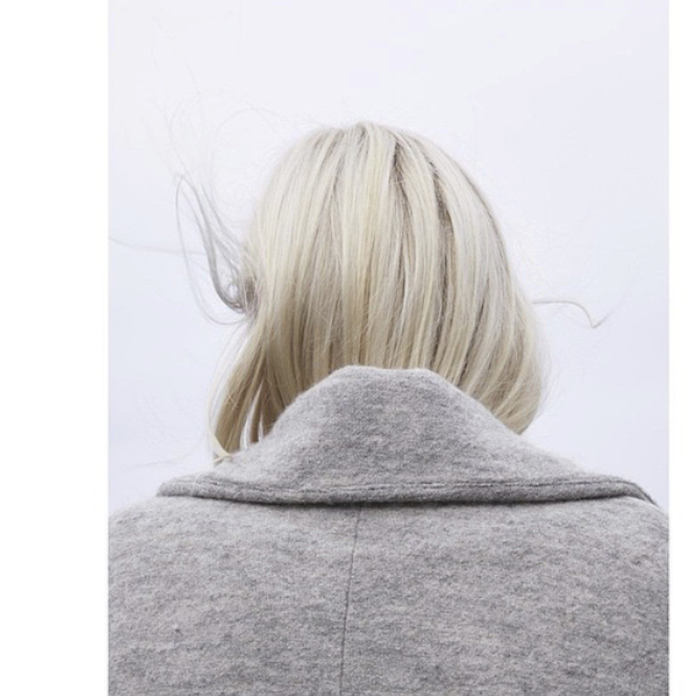 Platinablont hår instoppat i en grå kappa